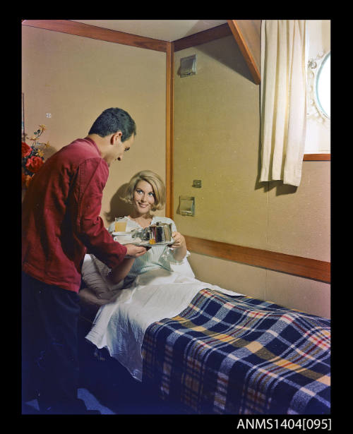 Photographic transparency showing a passenger aboard the ship FLAVIA being served breakfast in bed by a steward