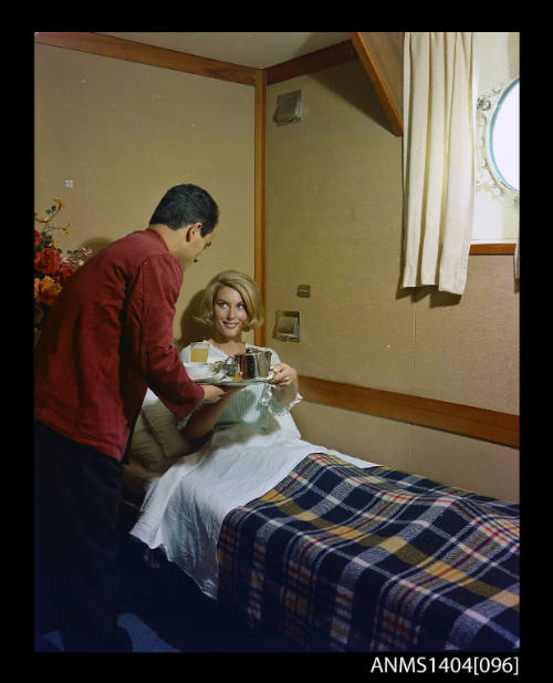 Photographic transparency showing a passenger aboard the ship FLAVIA being served breakfast in bed by a steward