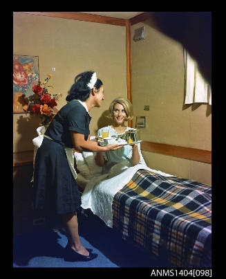 Photographic transparency showing a passenger aboard the ship FLAVIA being served breakfast in bed by a stewardess