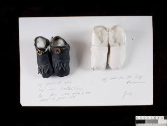Two pairs of miniature shoes mounted on board