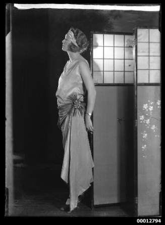 Woman in evening dress posing next to a folding screen