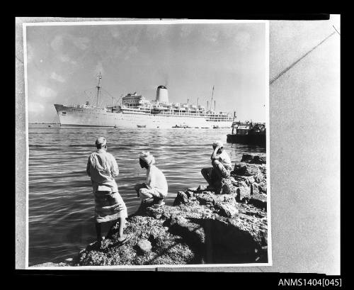 Three men watch SS ARCADIA II in the distance