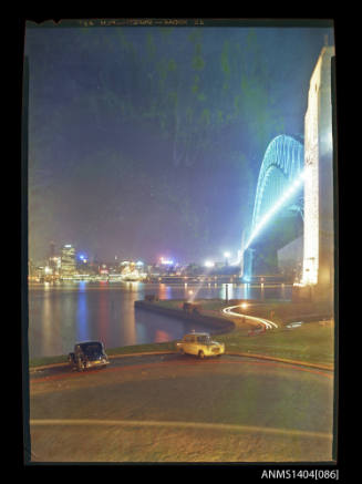 Photographic transparency showing the Sydney Harbour Bridge and Circular Quay at night time