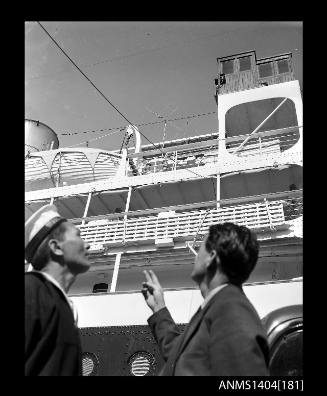 Photographic negative showing a sailor and a man looking at a television aerial on board the ship TAIPING