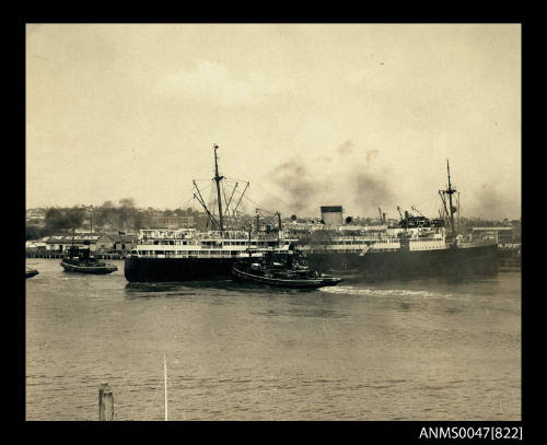 TSMV MANUNDA being maneuvered by three tugs near an Adelaide Steamship Company wharf