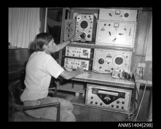 Photographic negative showing a man operating communications equipment on a boat