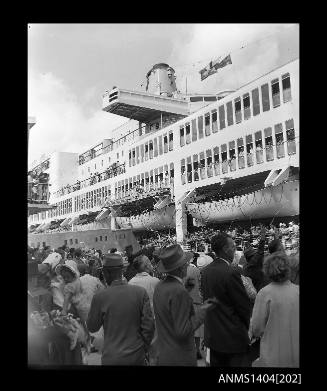 Photographic negative showing a crowd of people and a departing passenger ship at Circular Quay Overseas Passenger Terminal