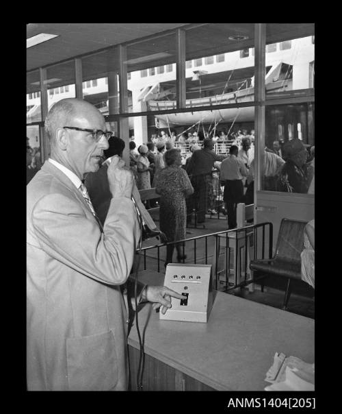 Photographic negative showing a man using the loud speaker system at Circular Quay Overseas Passenger Terminal