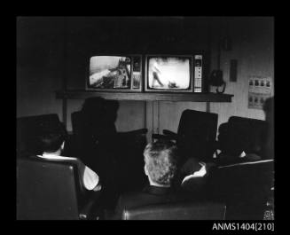 Photographic negative showing three men looking at two television sets on board the ship AUSTRALIAN TRADER