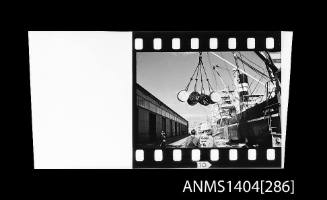 Photographic negative strip showing metal drums being loaded onto a cargo ship