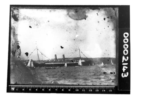 A dressed two-masted steamship on Sydney Harbour, surrounded by yachts and smaller vessels