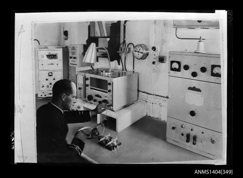 Photographic negative showing a ship's operator sitting at the radio panel on board a ship