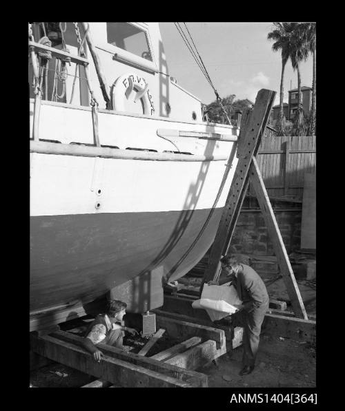 Photographic negative showing two men next to a vessel in dry dock at Kirribilli