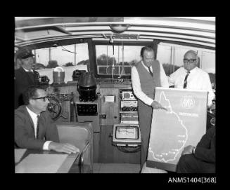 Photographic negative showing a group of men on board a boat with a poster of the AWA Australian radio network