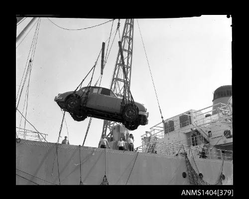 Photographic negative showing a Jaguar car being loaded onto a cargo vessel