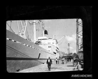Photographic negative showing a ship moored alongside a wharf with people on it