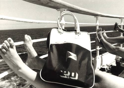 Photograph depicting the legs of some people sunbathing and a P&O bag