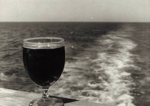 Photograph depicting a glass of a cold beverage on a ship's stern