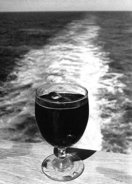 Photograph depicting a glass of a cold beverage on a ship's stern