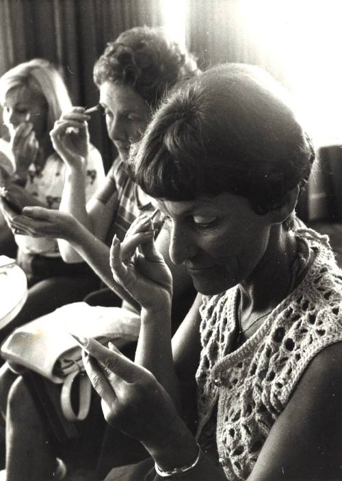 Photograph depicting three women applying makeup