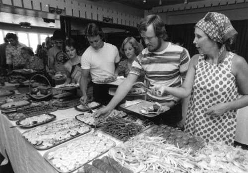 Photograph depicting a group of people serving themselves from a buffet