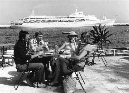 Photograph depicting a group of people having a drink with CANBERRA in the background