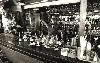 Photograph depicting a barman at a bar preparing cocktails