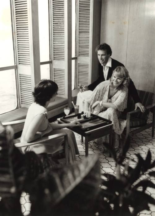 Photograph depicting three people playing backgammon