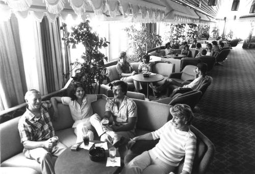 Photograph depicting a group of people sitting at a ship's saloon