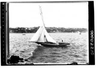 A gaff cutter, possibly KELPIE, with two people visible onboard, Sydney Harbour