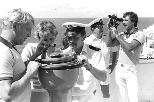 Photograph depicting a man using a sextant and a couple looking at a compass