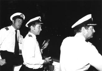 Photograph depicting the captain and two officers on ORIANA's bridge