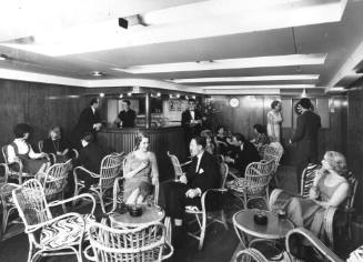 Photograph depicting a group of people sitting at ship's saloon