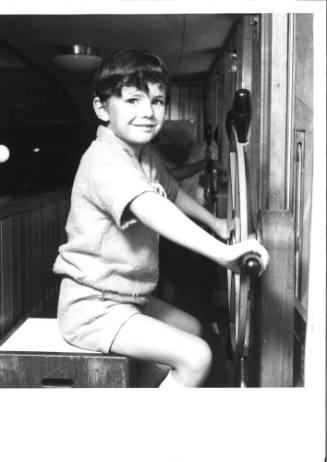 Photograph depicting a child playing with a ship's wheel