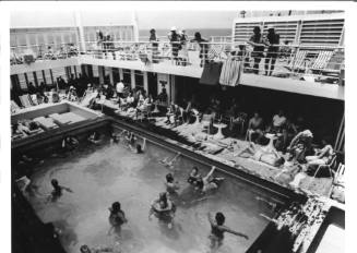 Photograph depicting passengers by the ship's pool