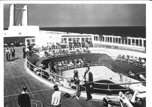 Photograph depicting passengers by the ship's pool onboard CANBERRA