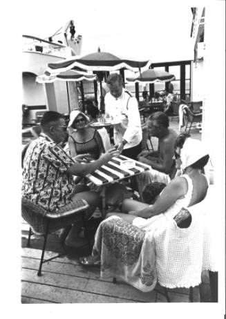 Photograph depicting passengers sitting on deck