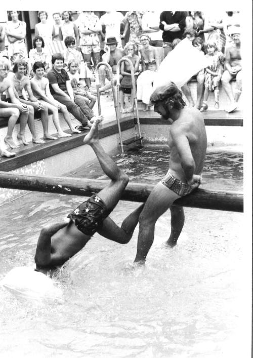 Photograph depicting two men playing greasy pole