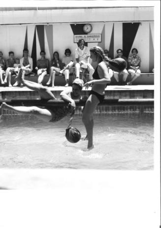 Photograph depicting two women playing greasy pole