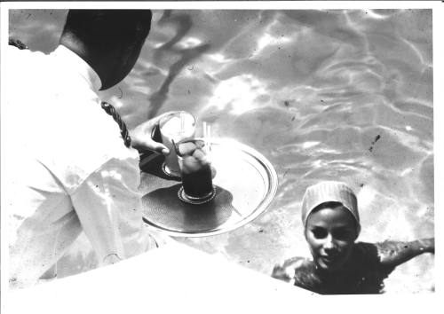 Photograph depicting a woman having a drink in the pool