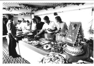 Photograph depicting a group of people serving themselves from a buffet