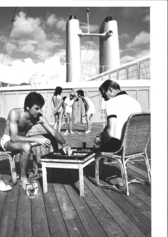 Photograph depicting two men playing a board game on deck