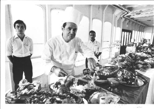 Photograph depicting a chef posing next to a food display