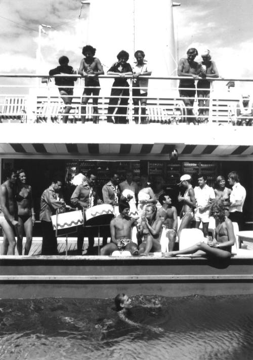 Photograph depicting passengers sunbathing by the edge of the ship's pool