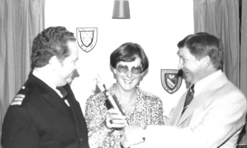 Photograph depicting three people with a trophy