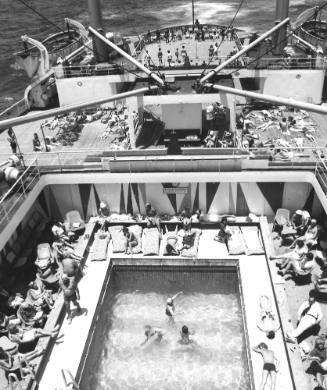 Photograph depicting passengers relaxing by the ship's pool