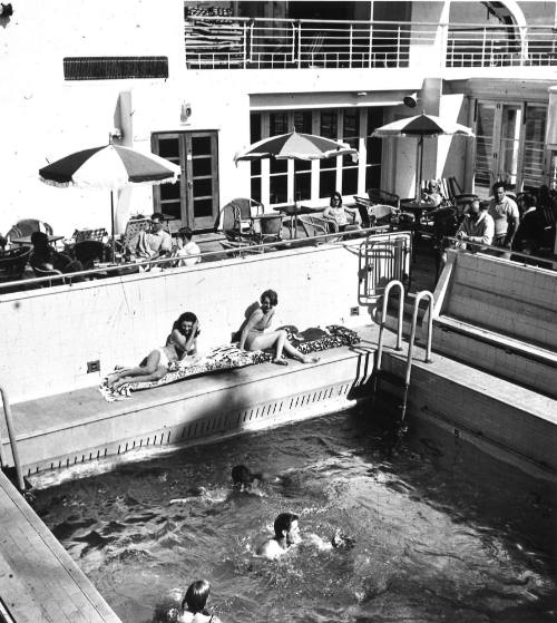 Photograph depicting passengers relaxing by the ship's pool