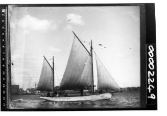 Starboard view of a gaff ketch under sail on Sydney Harbour with the name 'M LISS' in dark letters on the bulwark near the bow