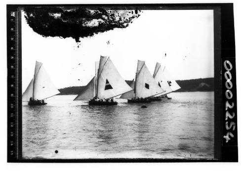 Large open boats, likely 22-footers  racing on Sydney Harbour displaying a var