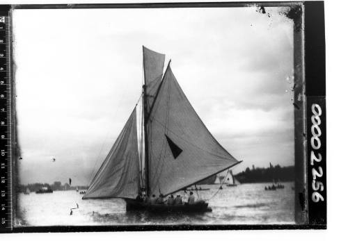 Yacht displaying a triangle emblem on the mainsail on Sydney Harbour, likely the 22-footer PLOVER